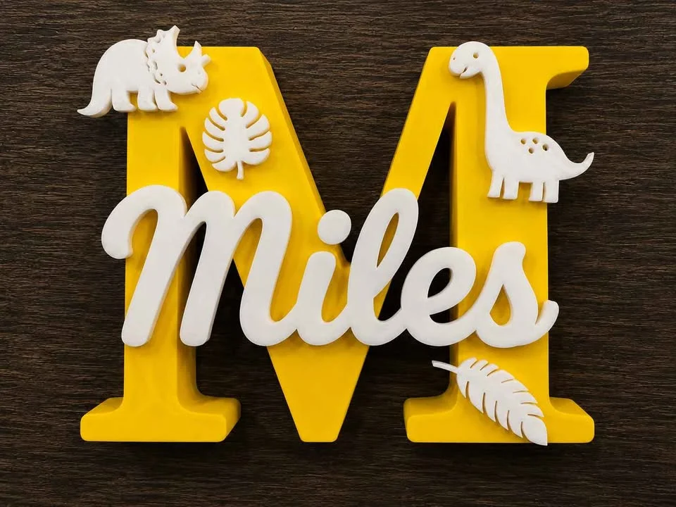 Illustration: yellow letter M name sign with a white name and dinosaurs