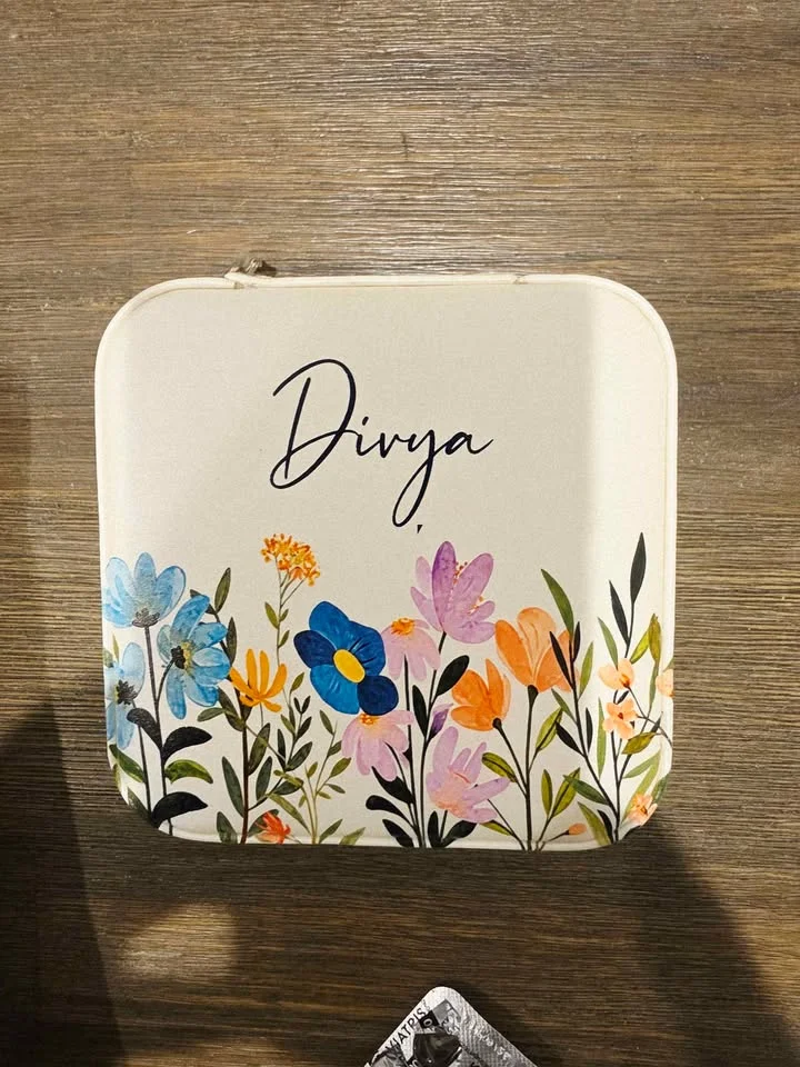 Top view of an off-white jewellery box with a name in script above colourful wildflowers
