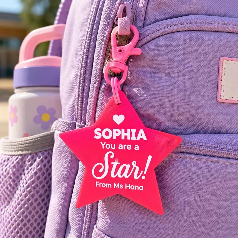 Illustration: pink "You are a Star" keychain clipped to a school backpack