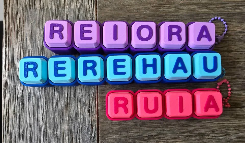 Three clicky keyboard-key name keychains in purple, light blue and pink with bead chains